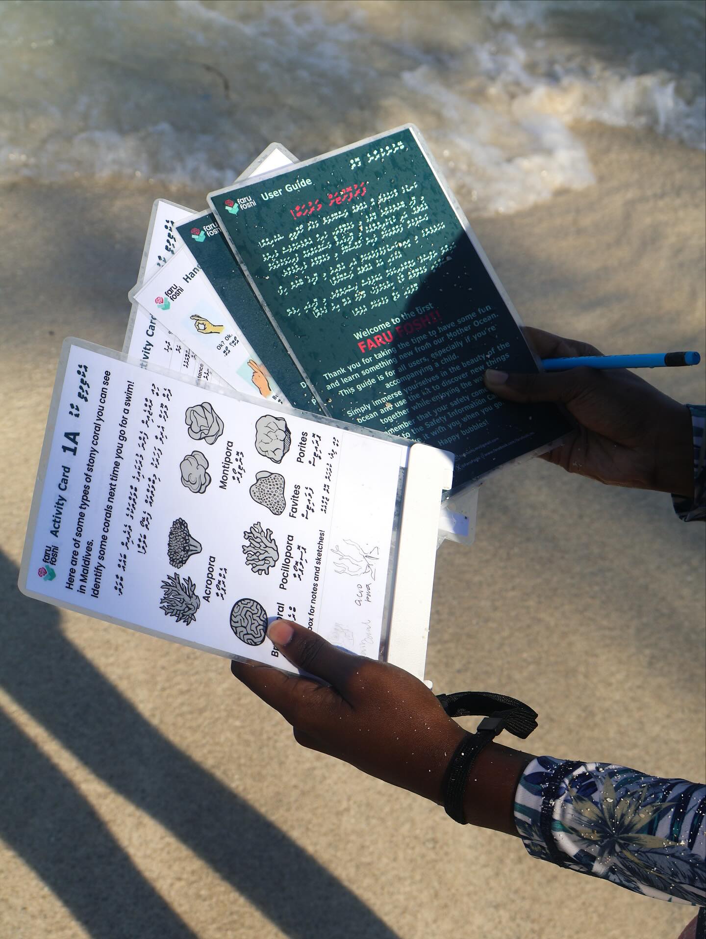 Child holding activity cards by the sea