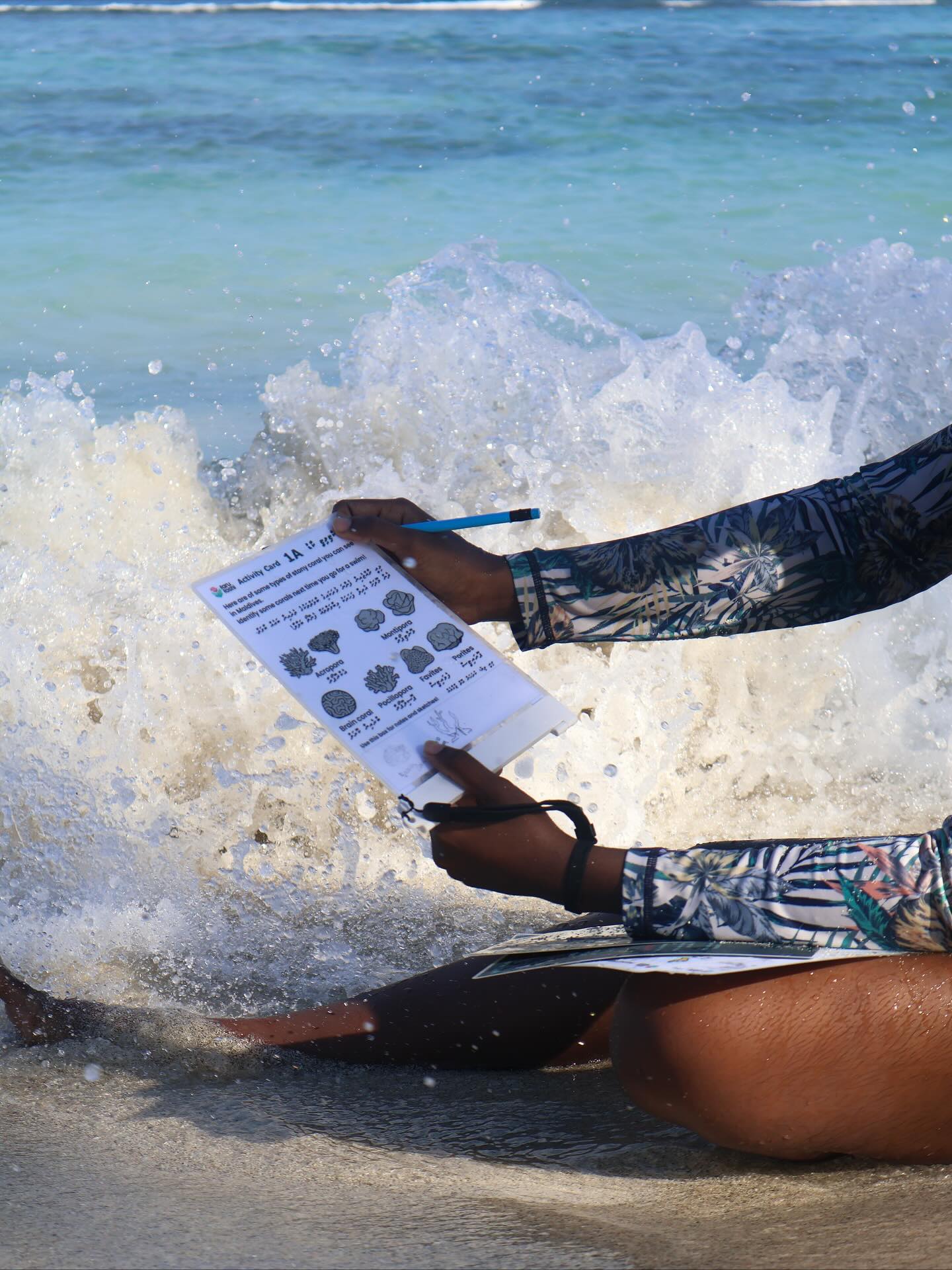 Citizen scientist with coral activity card in the waves